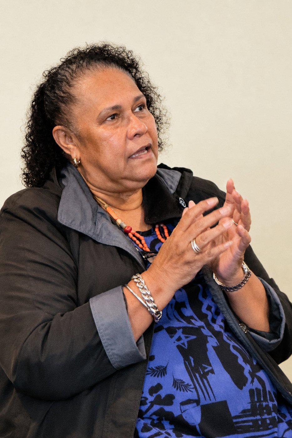 Aunty Sandra King, mid-sentence, hands clasped together expressively.