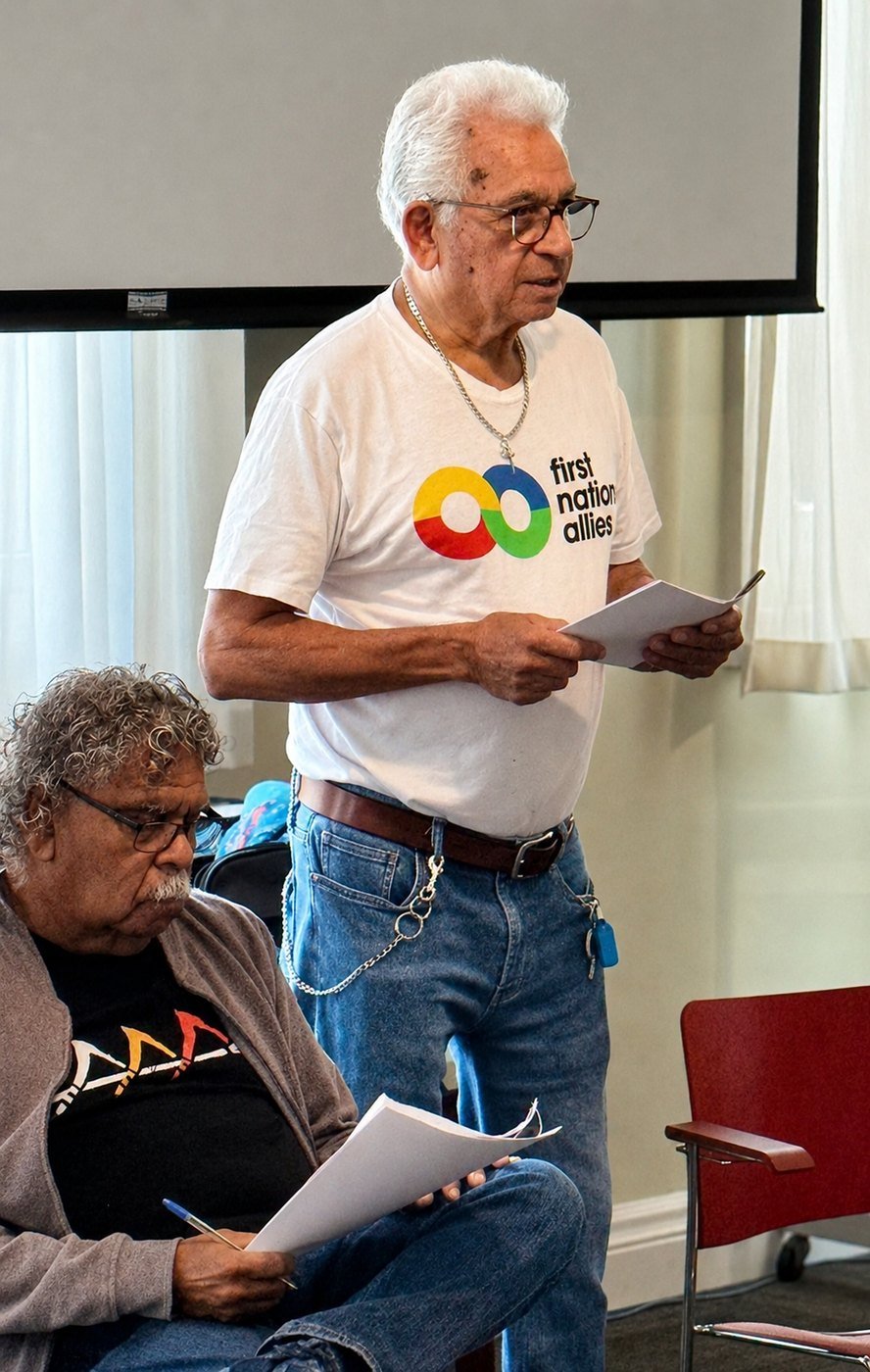Uncle Bill Lemson stands holding his notes, introducing Uncle Billy Gorham, who is seated in the foreground reading from his own notes.