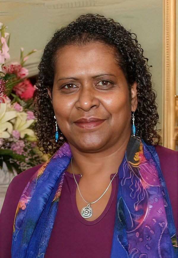 Dr Noritta Morseu-Diop, First Nations academic and social worker, smiling, wearing a purple top and silk scarf.