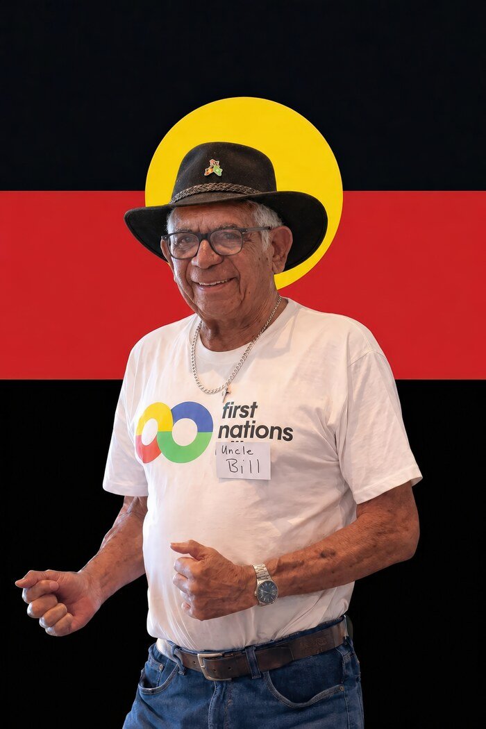 Uncle Bill Lemson, a Mitakoodi Elder, photographed in his hat in front of the Aboriginal Flag.